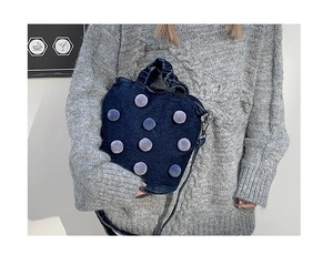 Detail of dark blue denim bucket bag with plush purple polka dots and pleated handle