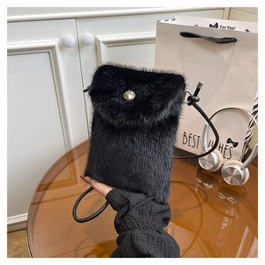 Detail einer flauschigen schwarzen Mini-Handytasche mit runder silberner Metallschnalle