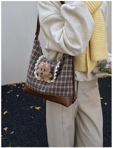 Detail of checkered shoulder bag with ruffle lace and cute plush bear on ginkgo leaf background