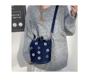 Detail of blue denim bucket bag with plush polka dots and silver metal strap hooks