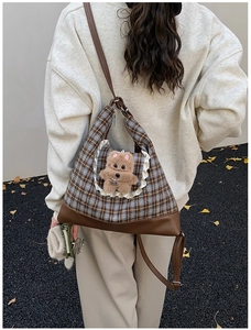 Detail of plaid kids crossbody bag featuring lace pocket and plush bear charm accessory