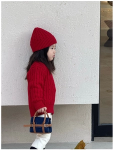 Detail of child's mini denim handbag with brown leather trim and red knit sweater
