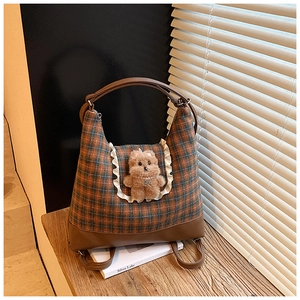 Detail of plaid tweed crossbody bag featuring lace trim and a cute plush bear charm
