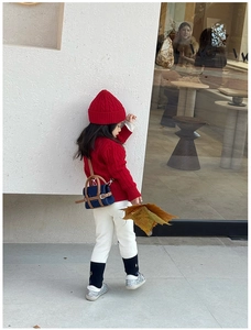 Detail showing a stylish blue and brown mini crossbody bag paired with a red knit sweater