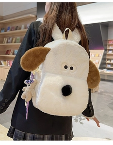 Close-up of fluffy white dog plush backpack with brown ears in a cozy bookstore setting