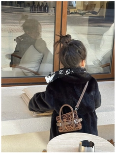 Mini leopard print crossbody bag with leather handles shown on a fuzzy faux fur coat