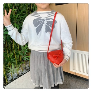 Close-up of red heart-shaped girls shoulder bag with bow detail on model outfit