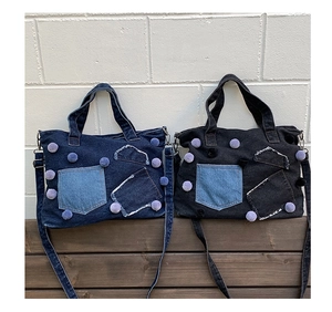 Borse tote in denim blu scuro e nero con ciondoli a pompon e tasche con dettagli sfrangiati