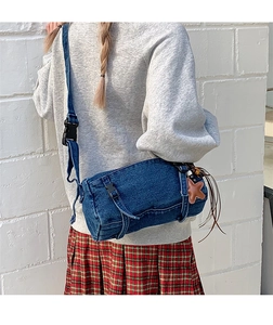 Détail d'un sac cylindre en jean avec breloque étoile marron et pompon à franges
