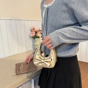 Mini golden synthetic leather handbag with bow detail for girls, shown in hand by model