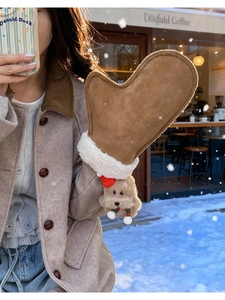 Detail of brown suede mittens with plush trim and cute puppy charm in a snowy scene