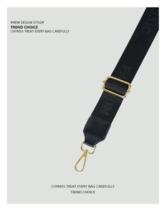 Detail of black woven shoulder strap with gold-tone hardware and embossed lettering