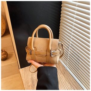 Close-up of mini khaki suede crossbody bag with leather strap and silver metal buckle