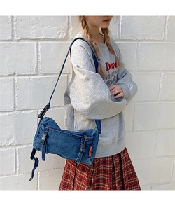 Détails de la bandoulière réglable et de l'étiquette orange du sac en jean bleu