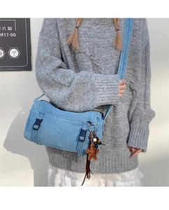 Détail du sac bandoulière en denim bleu clair avec boucles noires et breloque étoile
