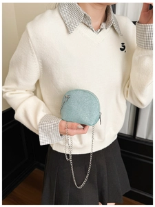 Detail of mint green shell crossbody bag with sequin texture and silver chain strap