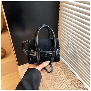 Detail of mini black crossbody bag with contrast stitching and suede texture
