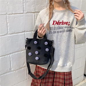Black denim bucket bag with purple pom-poms and adjustable crossbody strap for women