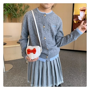 Detailed view of grey cable knit cardigan with blue embroidery and heart-shaped crossbody bag