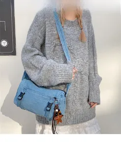 Détail du sac bandoulière en denim bleu avec boucles noires et pendentif étoile
