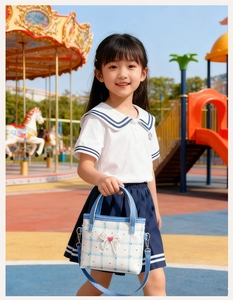 Detail der blau karierten Kindertasche mit Spitzenschleife und Herzen in Spielumgebung