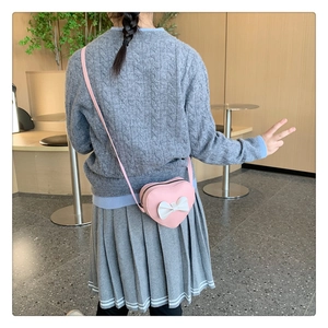 Sweet pink heart-shaped girl's crossbody bag with bow decoration worn by a model