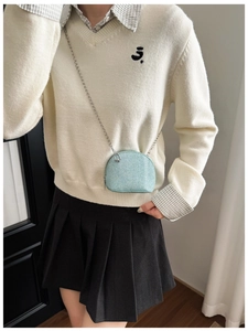 Detail view of light blue shell-shaped mini bag with textured fabric and silver chain