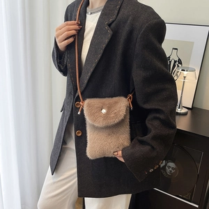Braune Plüsch-Handytasche mit Perlenschnalle an Model in dunklem Blazer getragen