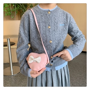 Detailed view of pink heart-shaped kids crossbody bag with white bow and gold zipper