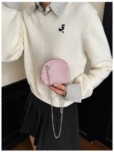 Detail view of pink glitter shell bag with silver chain strap held by a child model