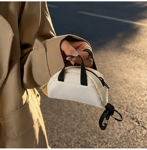 Detail of beige canvas mini pouch with black carabiner and zipper in golden hour light