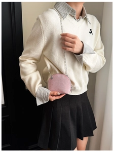 Pink corduroy shell-shaped crossbody bag with a silver chain strap on model