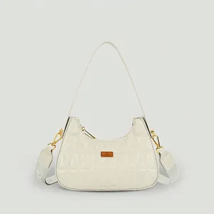 Quilted cream baguette bag with diamond stitching and adjustable woven shoulder strap