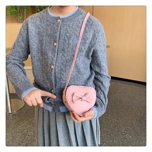 Detail of pink heart-shaped crossbody bag with decorative bow on a young girl
