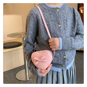 Detail of a pink heart-shaped kids shoulder bag with a bow knot and adjustable strap