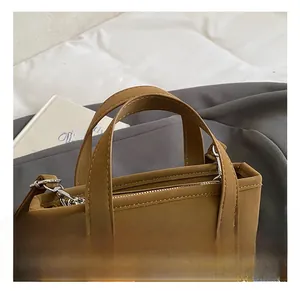 Detalle del bolso tote marrón con bordados coloridos y cierre de cremallera metálica
