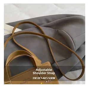 Detalle de la correa de cuero ajustable y el bordado en un bolso bandolera de color marrón