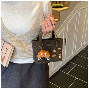 Detalle del bordado de café y tostada en el bolso marrón para niños con amuleto suave