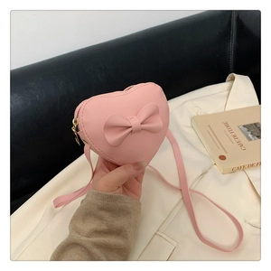 Detailed shot of a heart-shaped pink PU leather girls crossbody bag with bow decoration