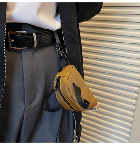 Detail of a mustard yellow mini utility pouch hanging on trousers as a waist accessory