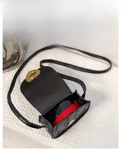 Vue macro du mini sac croco montrant la capacité intérieure et la boucle en forme de cœur