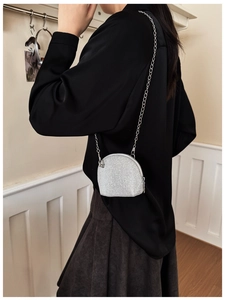 Detail of a sparkling shell-shaped mini bag with silver sequins and metal chain