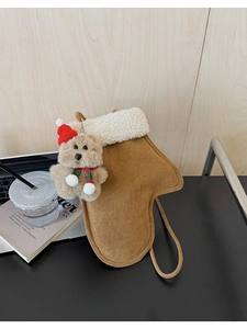 Detail of Christmas glove-shaped crossbody bag with a plush bear charm on a desk