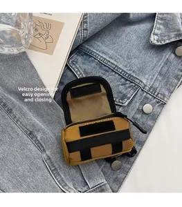 Nahaufnahme der khakifarbenen Mini-Segeltuchtasche mit Klettverschluss auf Jeansstoff