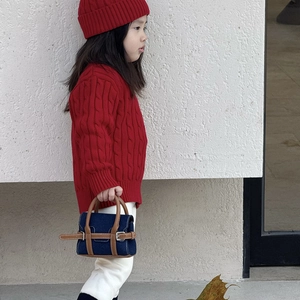 Girl in red knit sweater carrying a denim handbag with brown leather trim and metal buckle