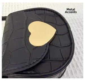 Détail d'un sac bandoulière noir à motif pierre avec une pièce de métal en cœur doré