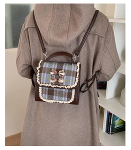 Detail of plaid kids backpack with lace trim and bow accents shown on a model