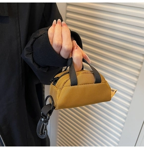 Mini mustard yellow nylon coin pouch with black handles and metal carabiner hook detail