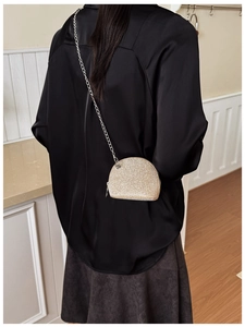 Detail of a sparkling shell-shaped mini bag with fine silver chain strap and zipper