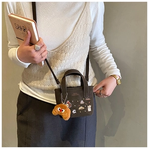 Detalle del mini bolso bandolera marrón oscuro con bordado y colgante de croissant de felpa